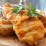 Crispy beer-battered fish and chips served with tartar sauce and lemon wedges.