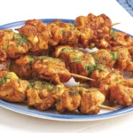 Plate of crispy Lemon Garlic Butter Chicken Spiedini skewers with garlic butter drizzle.
