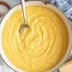 Creamy polenta served with parmesan cheese and fresh herbs in a bowl.