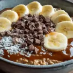 Bowl of overnight chocolate banana oats topped with sliced banana and chocolate chips