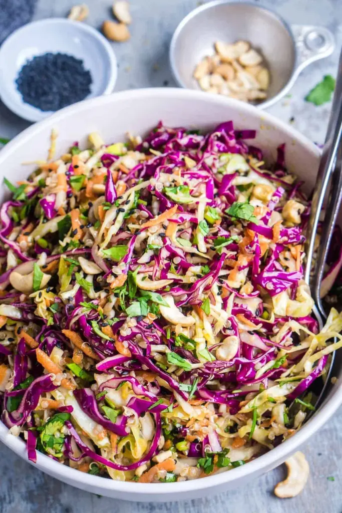 Bowl of Asian slaw topped with sesame ginger dressing and colorful fresh vegetables.