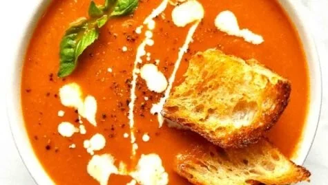 Bowl of homemade tomato soup topped with fresh basil and croutons