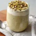 Bowl of creamy pistachio overnight oats topped with nuts and fruits