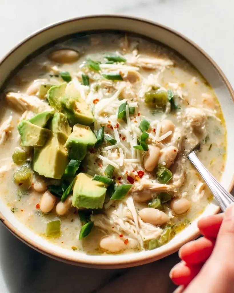 Bowl of slow cooker white chicken chili garnished with cilantro and avocado
